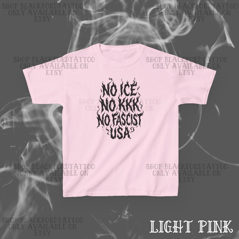 May include: Light pink t-shirt with the text "NO ICE, NO KKK, NO FASCIST, USA" in a black, flame-like design. The shirt also has the text "SHOP BLACKFORDTATTOO ONLY AVAILABLE ON ETSY" repeated around the shirt.
