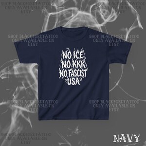 May include: Navy blue t-shirt with white text reading "NO ICE NO KKK NO FASCIST USA" in a flame-like design. The text is centered on the front of the shirt. The words "SHOP BLACKFORDTATTOO ONLY AVAILABLE ON ETSY" are printed around the shirt.