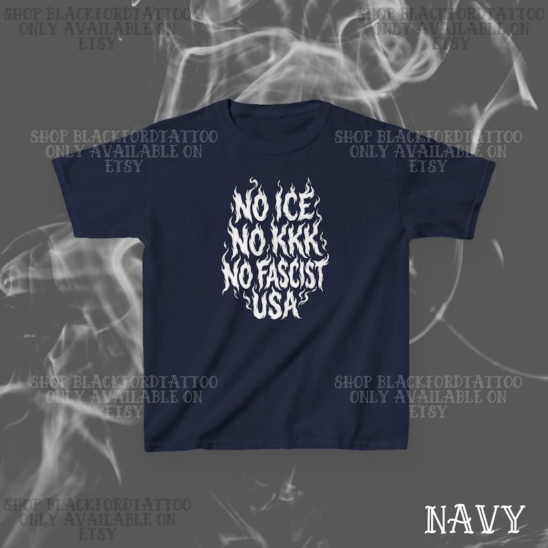 May include: Navy blue t-shirt with white text reading "NO ICE NO KKK NO FASCIST USA" in a flame-like design. The text is centered on the front of the shirt. The words "SHOP BLACKFORDTATTOO ONLY AVAILABLE ON ETSY" are printed around the shirt.