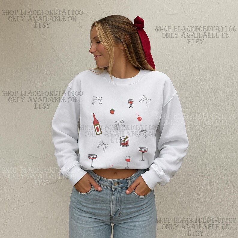 May include: White sweatshirt with a cocktail-themed design. The design includes illustrations of wine glasses, a bottle, cherries, strawberries, and bows. The text "SHOP BLACKFORDTATTOO ONLY AVAILABLE ON ETSY" is printed on the top and bottom of the image.