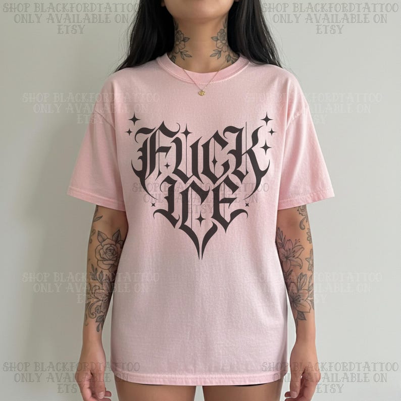May include: A light pink t-shirt with the words "FUCK ME" in a gothic font, designed in a heart shape. The shirt has short sleeves and a crew neck. The text "SHOP BLACKFORDTATTOO ONLY AVAILABLE ON ETSY" is printed on the top and bottom of the image.