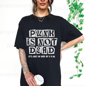 May include: Black t-shirt with a white graphic that says "Punk is not dead. It's just in bed by 9 p.m."