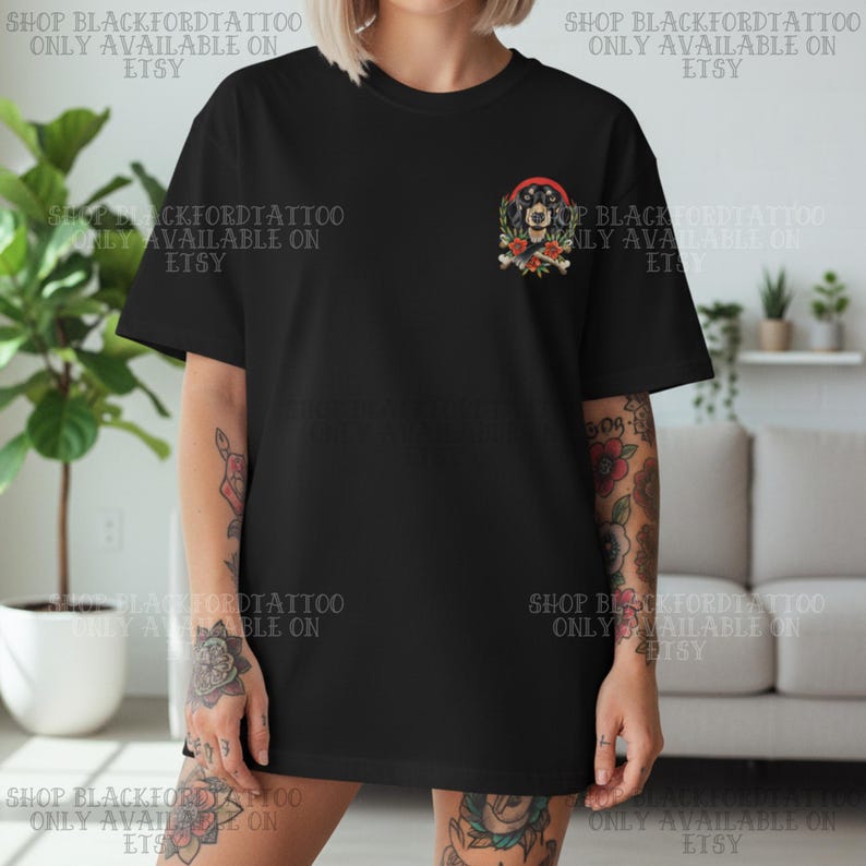 K&ouml;nnte beinhalten: Schwarzes T-Shirt mit einem farbenfrohen Tattoo-Design auf der Brust. Das Design zeigt ein Hundegesicht, Rosen und Knochen. Der Text "SHOP BLACKFORDTATTOO ONLY AVAILABLE ON ETSY" ist auf dem Shirt aufgedruckt.