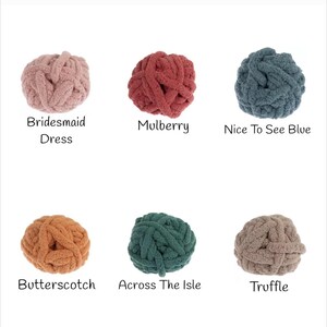 K&ouml;nnte beinhalten: Sechs Kn&auml;uel aus dickem Strickgarn in verschiedenen Farben: Bridesmaid Dress, Mulberry, Nice To See Blue, Butterscotch, Across The Isle und Truffle. Jedes Kn&auml;uel hat eine andere Farbe, mit den Namen der Farben unter jedem Kn&auml;uel.