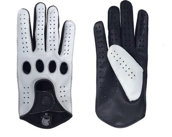 Puede incluir: Un par de guantes de conducir de cuero negro y blanco con detalles perforados. Los guantes tienen un cierre de presión en la muñeca.