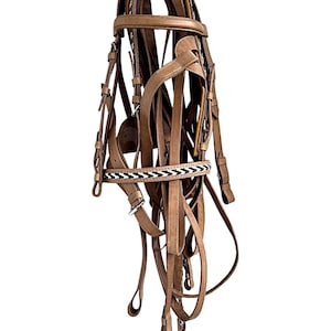 May include: A light brown leather horse bridle with multiple straps, buckles, and a decorative browband featuring a black and white pattern. The bridle is designed for equestrian use and is shown against a white background.
