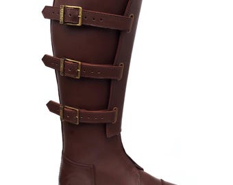 May include: A tall, brown leather riding boot with three adjustable buckle straps. The boot features a rounded toe and a high, protective shaft. The leather has a polished finish, and the buckles are gold-colored.