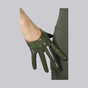 May include: A short, olive green glove with a glossy, smooth finish. The glove features a rounded wrist opening and covers the fingers and palm, leaving the wrist exposed. The material appears to have a slight sheen, reflecting light across its surface.