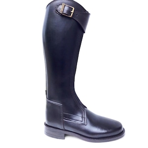 Może przedstawiać: Czarne skórzane buty do jazdy konnej z paskiem z klamrą i zamkiem błyskawicznym po wewnętrznej stronie buta.