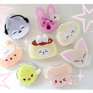 May include: A collection of cartoon character acrylic charms in various shapes, including a wolf with headphones, a pink bunny, a cat, a pudding, a fox with glasses, a chick with wings, and a dog. Each charm has a unique expression and color scheme.