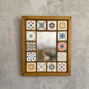 Può includere: Uno specchio con cornice in legno con un design decorativo di piastrelle colorate. Le piastrelle presentano vari motivi geometrici in tonalità di blu, giallo, arancio e rosso.