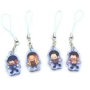 May include: Four cartoon character acrylic charms with blue lanyards. Each charm features a different character design with a light blue outline. The characters have various hairstyles and outfits, and are attached to silver-coloured metal clasps.