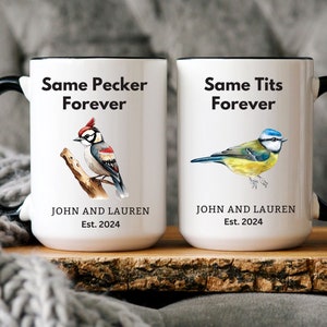 Op de afbeelding: Twee witte keramische mokken met zwarte handvatten. De mok links heeft een zwart-rode specht illustratie en de tekst "Same Pecker Forever". De mok rechts heeft een blauwe mees illustratie en de tekst "Same Tits Forever". Beide mokken hebben de tekst "John and Lauren Est. 2024".