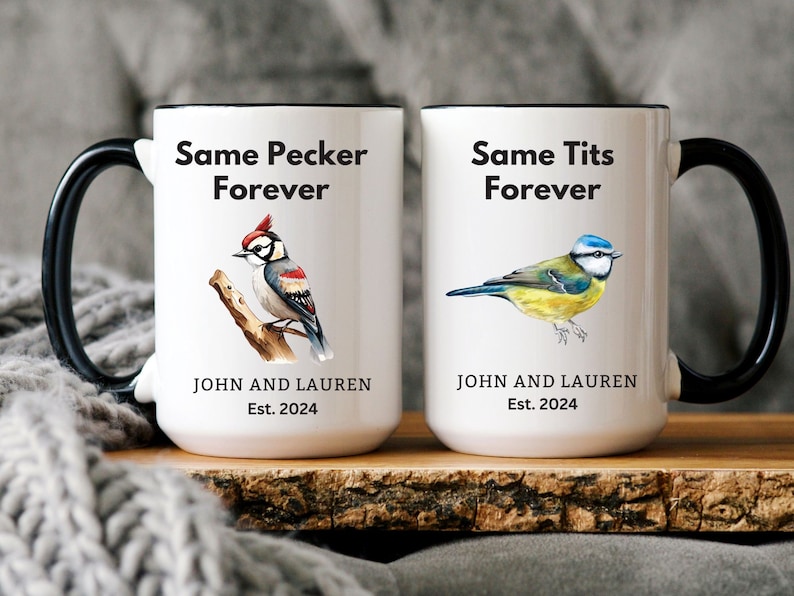 Op de afbeelding: Twee witte keramische mokken met zwarte handvatten. De mok links heeft een zwart-rode specht illustratie en de tekst "Same Pecker Forever". De mok rechts heeft een blauwe mees illustratie en de tekst "Same Tits Forever". Beide mokken hebben de tekst "John and Lauren Est. 2024".