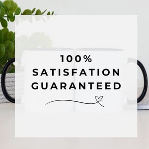 Promotional image featuring two white ceramic mugs with black handles in the background. A transparent overlay with bold black text reads '100% Satisfaction Guaranteed,' accompanied by a decorative heart flourish. Minimalist and modern design with greenery and a neutral backdrop.