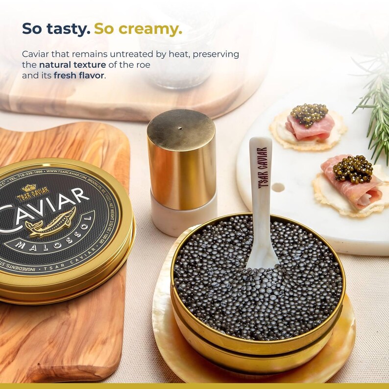 Puede incluir: Primer plano de un peque&ntilde;o recipiente redondo de oro lleno de caviar negro. Una cuchara blanca con las palabras "Tsar Caviar" impresas en ella descansa en el caviar. El recipiente est&aacute; sobre una superficie blanca y dorada. El texto "So tasty. So creamy." est&aacute; escrito en negro en la parte superior de la imagen. El texto "Caviar que permanece sin tratar por el calor, preservando la textura natural del huevo y su sabor fresco." est&aacute; escrito en negro debajo de la primera l&iacute;nea de texto.