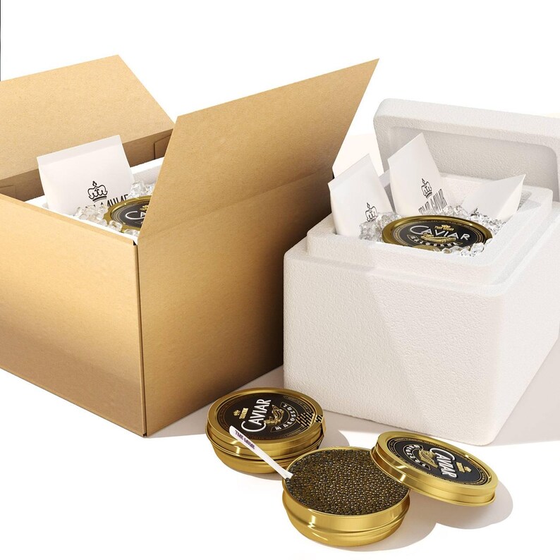 Puede incluir: Dos cajas de cart&oacute;n con las tapas abiertas, una contiene una nevera de poliestireno con un tarro de caviar y hielo, la otra est&aacute; vac&iacute;a. Dos peque&ntilde;os recipientes dorados con caviar y una cuchara est&aacute;n sobre una superficie blanca.
