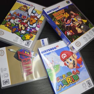 May include: Four Nintendo 64 video game cartridges are shown. The games include "Paper Mario", "Donkey Kong 64", "The Legend of Zelda: Ocarina of Time", and "Super Mario 64". Each game case features colourful artwork and the Nintendo 64 logo.