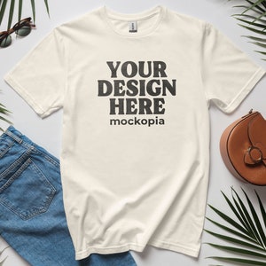 Op de afbeelding: Een wit T-shirt met korte mouwen en een ronde hals. Het shirt heeft de tekst "YOUR DESIGN HERE mockopia" op de voorkant.