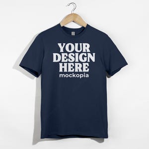 May include: A navy blue t-shirt with short sleeves and a white print that says "YOUR DESIGN HERE mockopia".