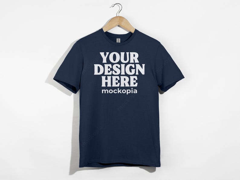 May include: A navy blue t-shirt with short sleeves and a white print that says "YOUR DESIGN HERE mockopia".