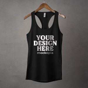 K&ouml;nnte beinhalten: Schwarzes Tanktop mit Racerback-Design. Das Tanktop hat den Text "YOUR DESIGN HERE" und "mockopia" auf der Vorderseite.