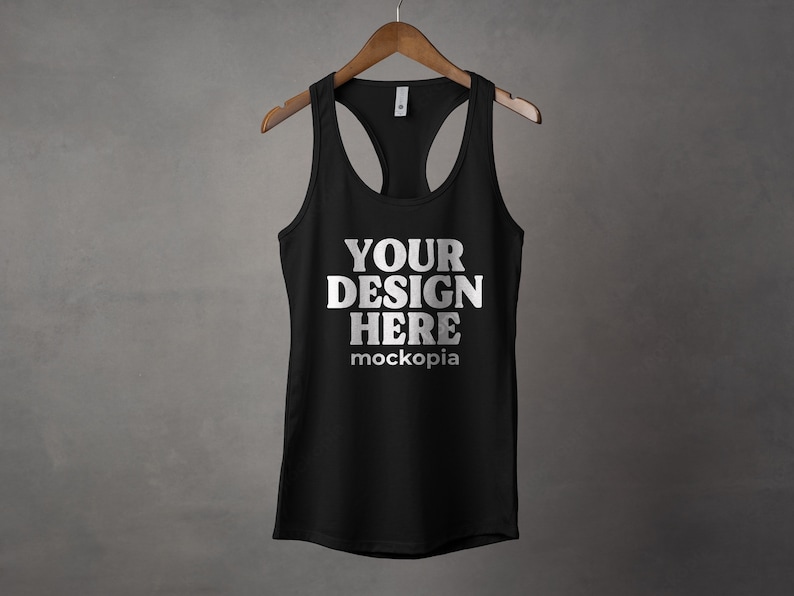 K&ouml;nnte beinhalten: Schwarzes Tanktop mit Racerback-Design. Das Tanktop hat den Text "YOUR DESIGN HERE" und "mockopia" auf der Vorderseite.