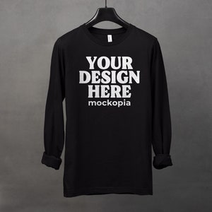 May include: Black long-sleeve t-shirt with the text "YOUR DESIGN HERE" and "mockopia" printed in white.