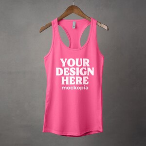 K&ouml;nnte beinhalten: Ein pinkfarbenes Tanktop mit Rundhalsausschnitt und Racerback-Design. Der Text "YOUR DESIGN HERE" ist in Wei&szlig; auf der Vorderseite des Tanktops aufgedruckt.