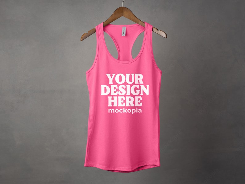 K&ouml;nnte beinhalten: Ein pinkfarbenes Tanktop mit Rundhalsausschnitt und Racerback-Design. Der Text "YOUR DESIGN HERE" ist in Wei&szlig; auf der Vorderseite des Tanktops aufgedruckt.