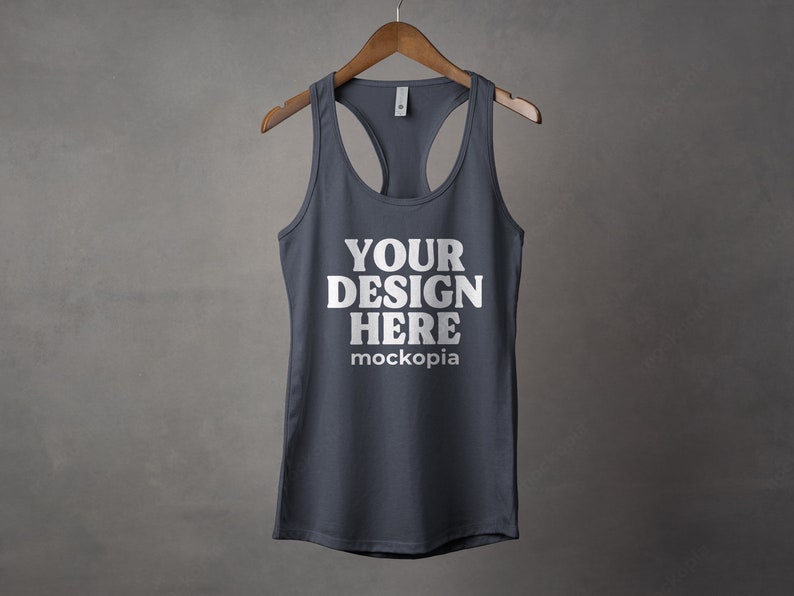 K&ouml;nnte beinhalten: Ein dunkelgraues Tanktop mit Racerback-Design. Das Tanktop hat den Text "YOUR DESIGN HERE" und "mockopia" auf der Vorderseite aufgedruckt.