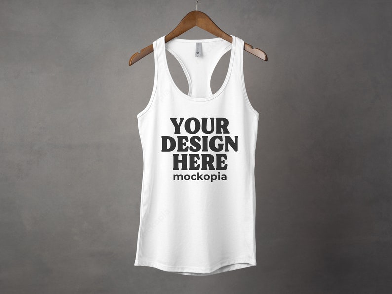 K&ouml;nnte beinhalten: Wei&szlig;es Tanktop mit Racerback-Design. Das Tanktop hat den Text "YOUR DESIGN HERE" und "mockopia" auf der Vorderseite.