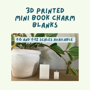 May include: Two white 3D-printed mini book charm blanks, one rectangular and one square, with a small loop at the top. Text reads "3D PRINTED MINI BOOK CHARM BLANKS" and "1:6 AND 1:12 SCALES AVAILABLE". A potted plant is in the background.