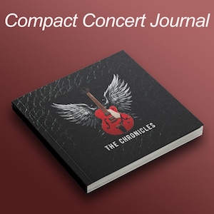 May include: A black journal titled "Compact Concert Journal" with a red guitar and white wings graphic. The text "THE CHRONICLES" is printed below the graphic. The journal is on a dark red background.