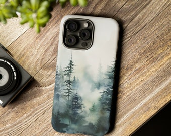 Op de afbeelding: Een smartphonehoesje met een aquarelillustratie van een dicht, mistig bos met donkergroene en blauwe dennenbomen die vervagen in een zachte, lichte achtergrond. Het hoesje heeft een uitsparing voor een camera met drie lenzen.