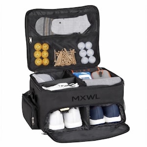 May include: A black golf locker bag with the text MXWL printed on the front. The bag is open, revealing multiple compartments containing yellow and white golf balls, wooden tees, a pair of white shoes, a pair of blue shoes, and various accessories.