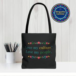 Könnte beinhalten: Schwarze Tragetasche mit dem Text "Love my culture? Love my people." in Türkis, Gelb und Grün. Die Tasche hat ein florales Design oben und unten. Ein runder Aufkleber mit den Worten "Orgullo Latino" befindet sich in der oberen rechten Ecke.