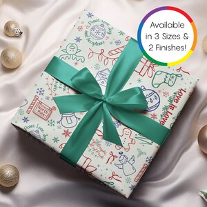 May include: A wrapped gift with festive wrapping paper featuring holiday-themed illustrations in red, blue, and green. The gift is tied with a teal satin ribbon. Text on the image says "Available in 3 Sizes & 2 Finishes!"