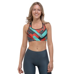 May include: A sports bra with a geometric pattern in shades of red, teal, black, and gray. The bra has a racerback style and is made of a stretchy, breathable fabric.
