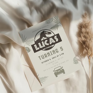 Puede incluir: Una invitaci&oacute;n de cumplea&ntilde;os con tem&aacute;tica de dinosaurios. La invitaci&oacute;n presenta el nombre "Lucas" y el texto "Turning 5". El dise&ntilde;o incluye una silueta de dinosaurio, hojas de palma y una ilustraci&oacute;n de jeep. La invitaci&oacute;n est&aacute; impresa en una tarjeta beige claro.