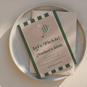 May include: A green, white, and pink invitation card with a striped pattern. The card reads "Let's Pickle! Amber's 30th" and includes details for a pickleball party.