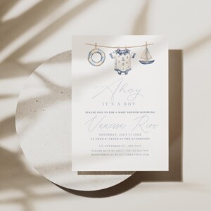 May include: A baby shower invitation with a nautical theme. The invitation features watercolor illustrations of a life preserver, a onesie, and a sailboat hanging on a clothesline. The text reads "Ahoy, It's a Boy" and includes event details.