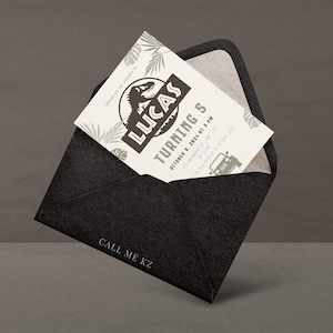 Puede incluir: Un sobre negro con una tarjeta de invitaci&oacute;n blanca. La tarjeta presenta el nombre "LUCAS" y el texto "TURNING 5" con un dise&ntilde;o de dinosaurio. El sobre tiene el texto "CALL ME KZ" impreso.