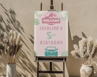 Puede incluir: Un cartel de bienvenida rosa y verde con una silueta de dinosaurio, el texto "Bienvenido Catalina's 5th Birthday" y una silueta de jeep verde.
