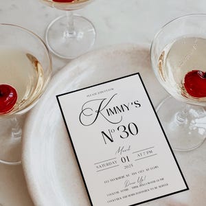 Puede incluir: Una tarjeta de invitaci&oacute;n en blanco y negro con una fuente cursiva que dice "Kimmy's N&deg; 30". La invitaci&oacute;n es para una fiesta el s&aacute;bado 1 de marzo de 2025 a las 7 PM. La direcci&oacute;n es 123 Anywhere St, Any City, ST 12345. El c&oacute;digo de vestimenta es "&iexcl;V&iacute;stete!" y la invitaci&oacute;n indica que se servir&aacute;n c&oacute;cteles y aperitivos.