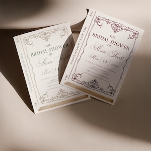 May include: Ivory bridal shower invitations with burgundy and gold detailing. The invitations feature decorative borders and the text "The Bridal Shower of Alexa Scott" with event details. The phrase "Her Next Chapter Begins" is also present.