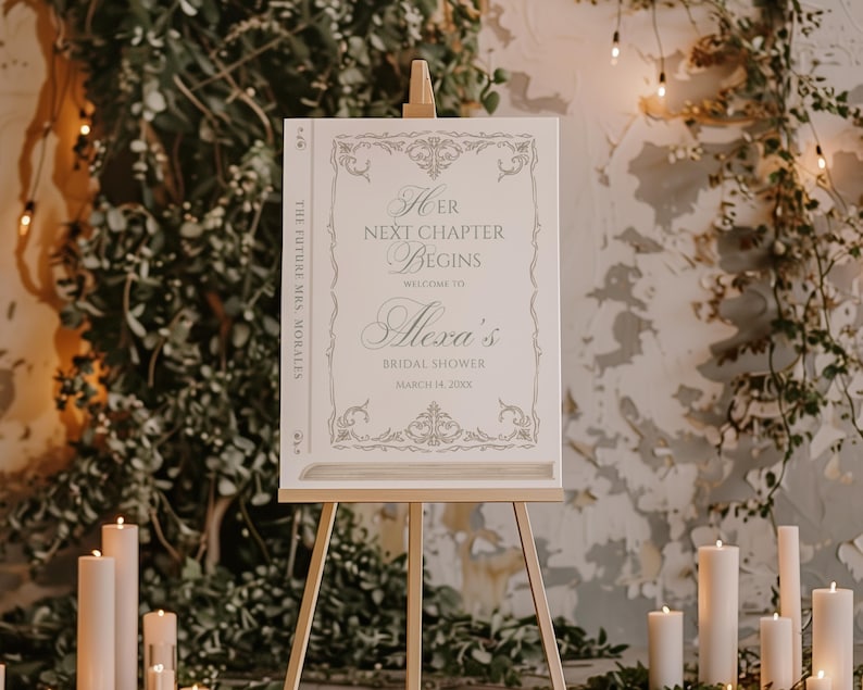 Puede incluir: Un letrero blanco sobre un caballete de madera con el texto "Her Next Chapter Begins" y "Alexa's Bridal Shower". El letrero tiene bordes decorativos y est&aacute; rodeado de velas y vegetaci&oacute;n, creando un ambiente festivo.