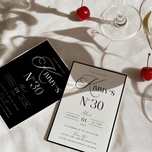 Puede incluir: Dos invitaciones en blanco y negro con el texto "Kimmy's N&deg;30" y detalles para una fiesta el 1 de abril de 2025 a las 7 PM. Las invitaciones est&aacute;n sobre una superficie blanca con cerezas rojas.