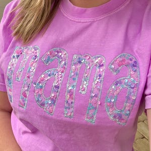 May include: A purple t-shirt with the word "mama" spelled out in iridescent sequins.