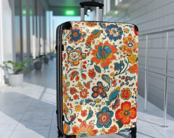 May include: A rolling suitcase with a vibrant floral pattern in orange, blue, and yellow on an off-white background. The suitcase has a black frame, handle, and wheels, and is designed for travel.